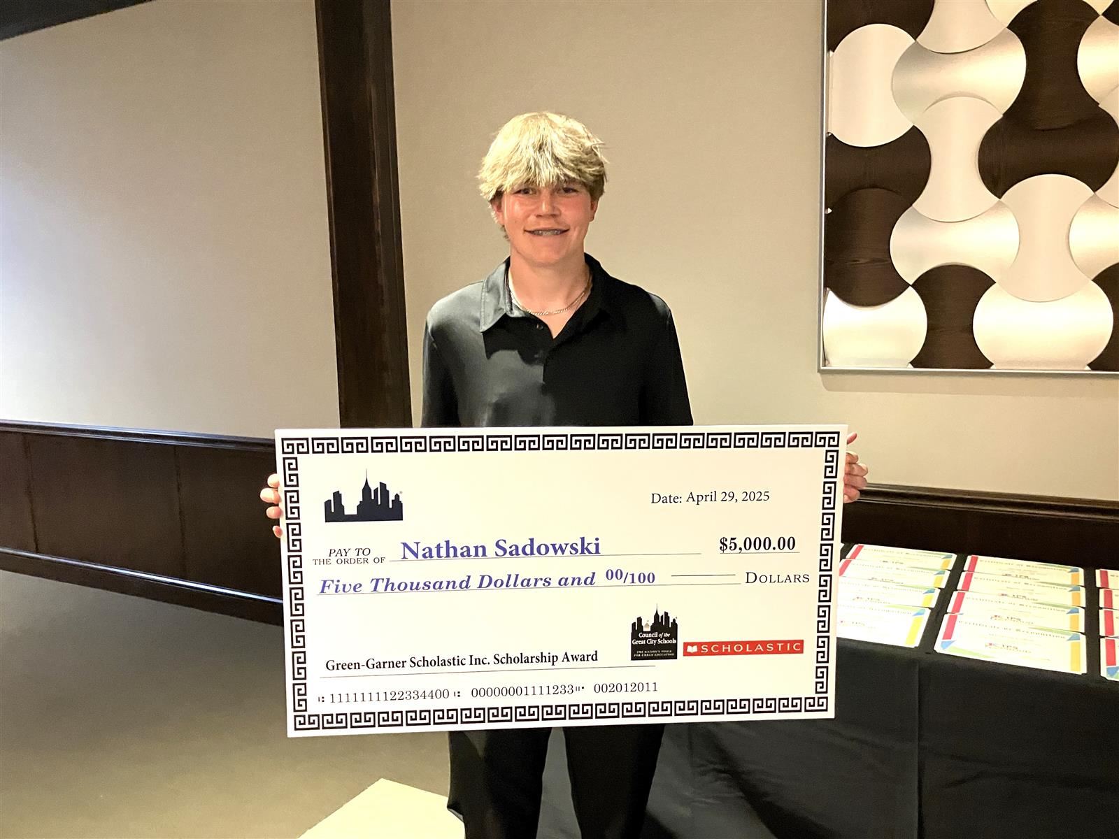 TPS Student, Nathan Sadwoski holding the Green Garner scholarship award granted by Superintendent, Romules Durant